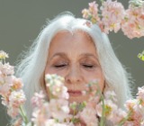 mature woman with her eyes closed behind flowers